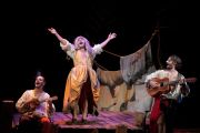 Foto di scena. Personaggi che suonano e cantano