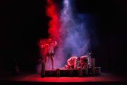 Foto di scena. Personaggi al buio dietro a del fumo colorato
