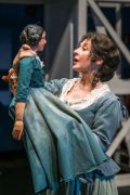 Foto di scena. Donna tiene in mano una bambola uguale a lei 