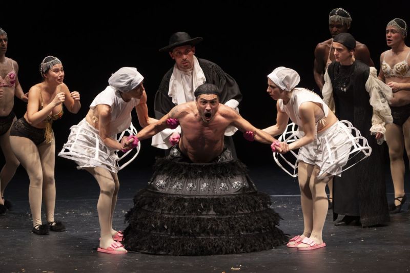 Foto di scena. Re Chicchinella tenuto da due ballerine vestite di bianco