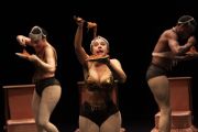 Foto di scena. Ballerine/attrici che si muovo sul palco mangiando spaghetti