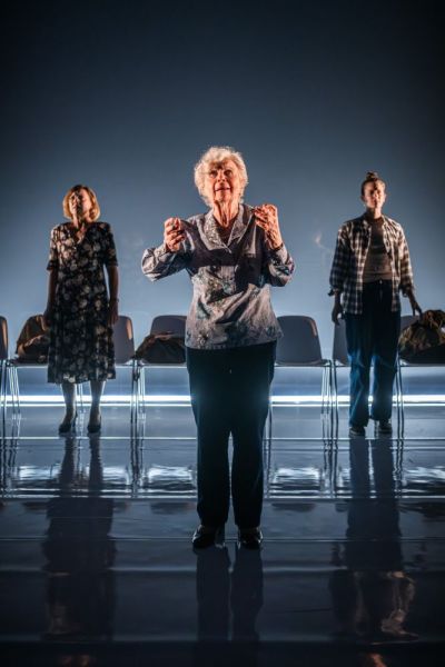 Foto di scena. Ariella Reggio, Maria Ariis e Lucia Limonta in piedi guardano verso il pubblico