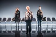 Foto di scena. Ariella Reggio, Maria Ariis e Lucia Limonta in piedi guardano verso il pubblico