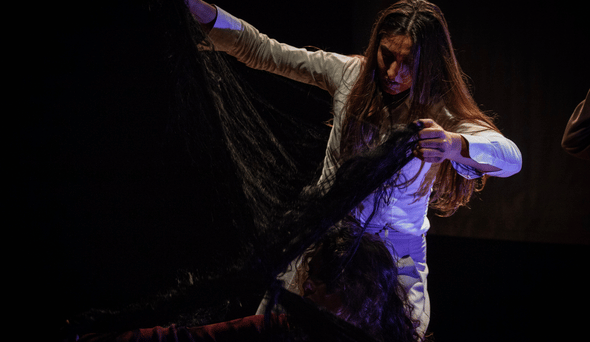 Foto di scena di una donna che prende in mano i capelli si un'altra donna